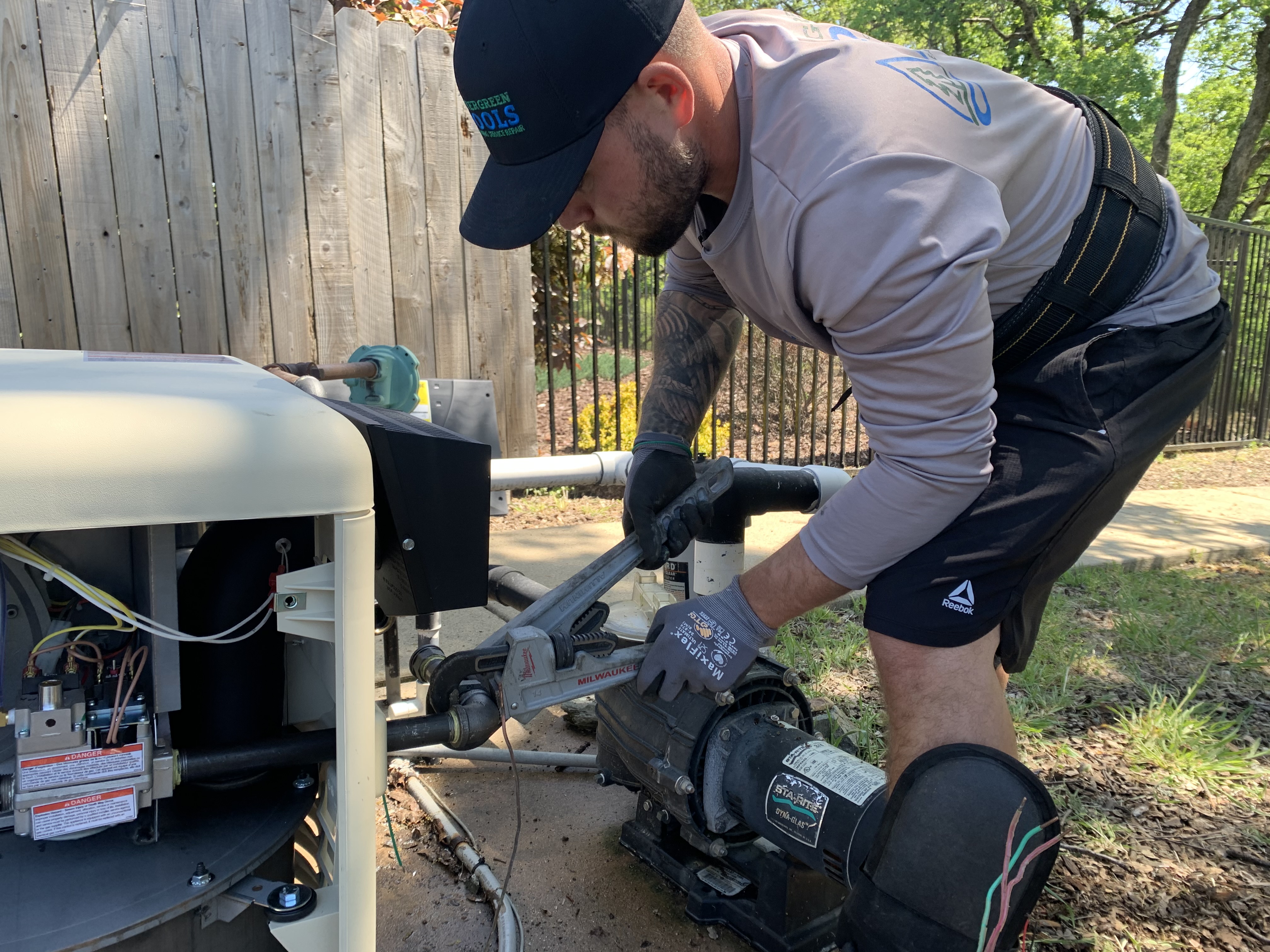 Vintage Pool Service tech servicing pool equipment with hose
